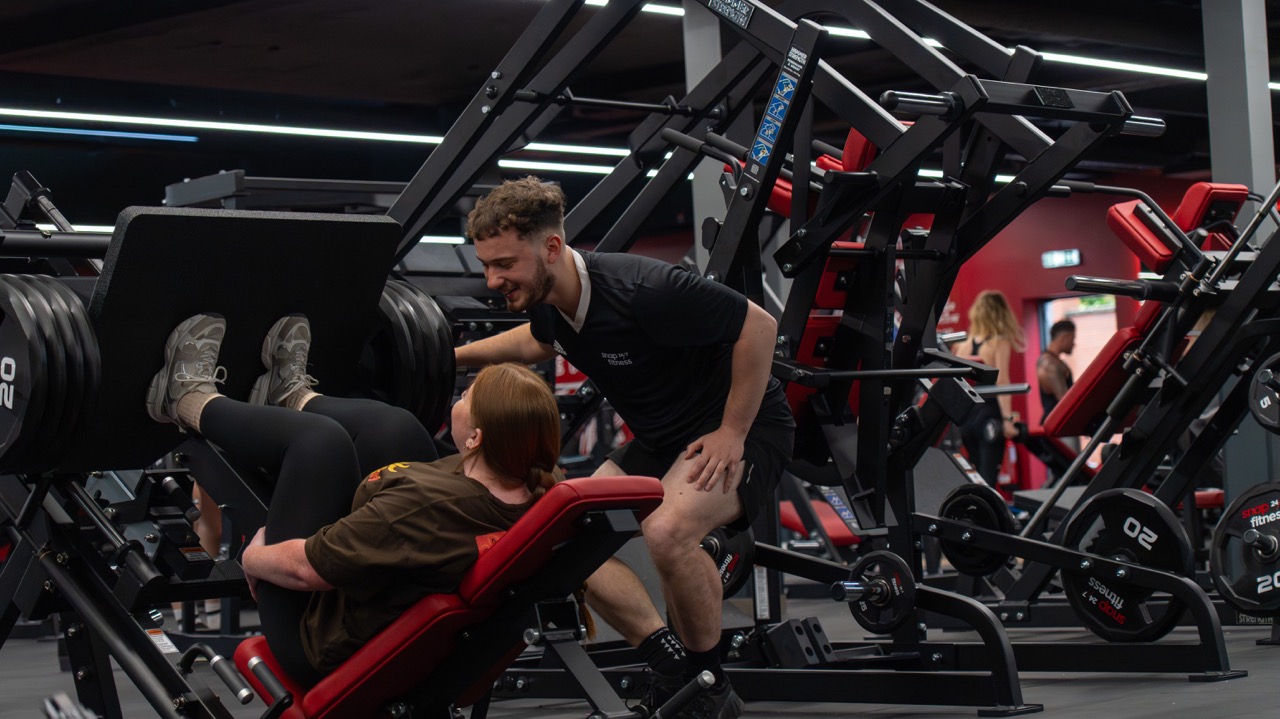 Elliott coaching a client on the leg press at Snap Fitness Redditch