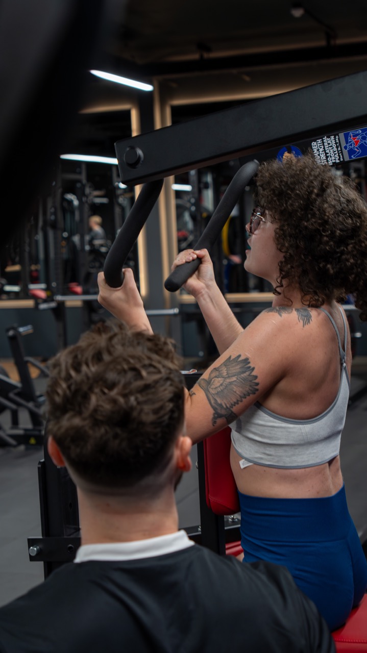 Elliott coaching a client on a chest press machine