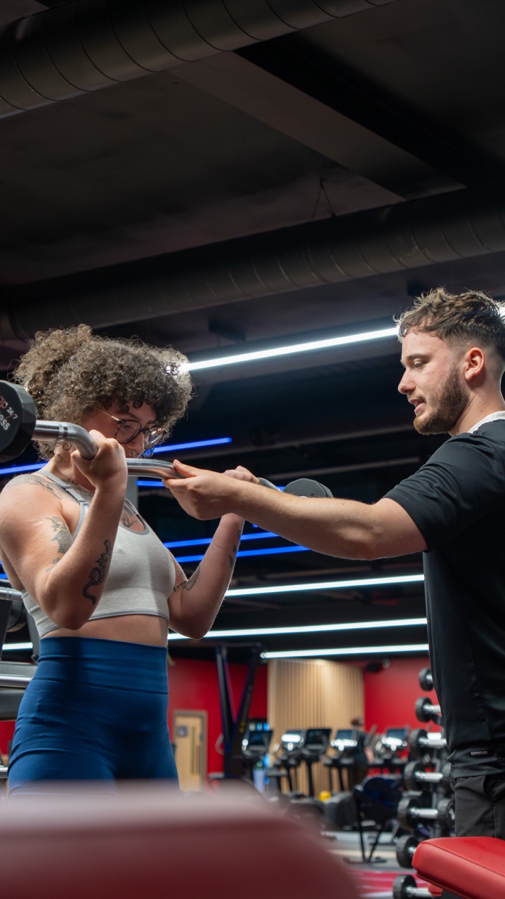 Elliott coaching a client through a barbell curl